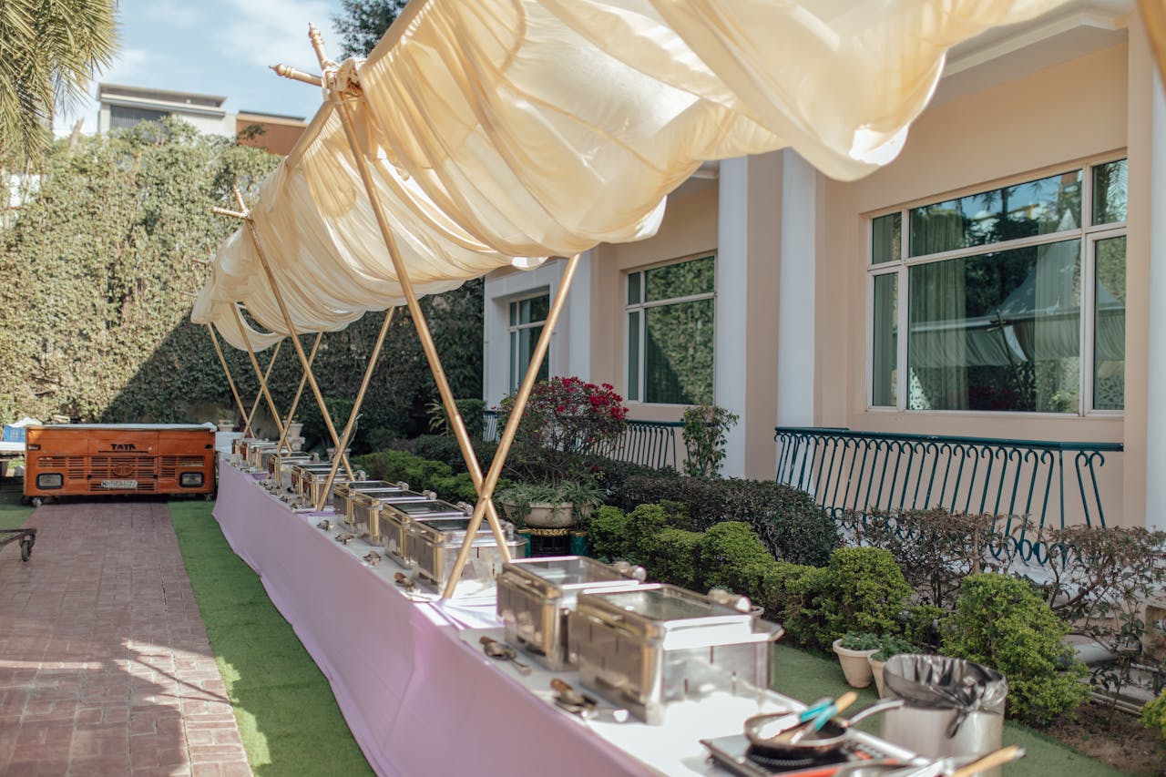 Elegant outdoor buffet setup with chafing dishes and canopy. Perfect setting for a garden party or wedding reception.
